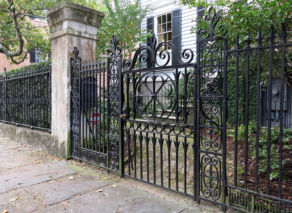 Ornate black wrought-iron fence and pedestrian gate in front of a home