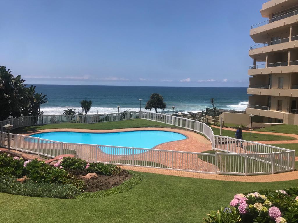 White metal pool safety fence enclosing a swimming pool with lawns